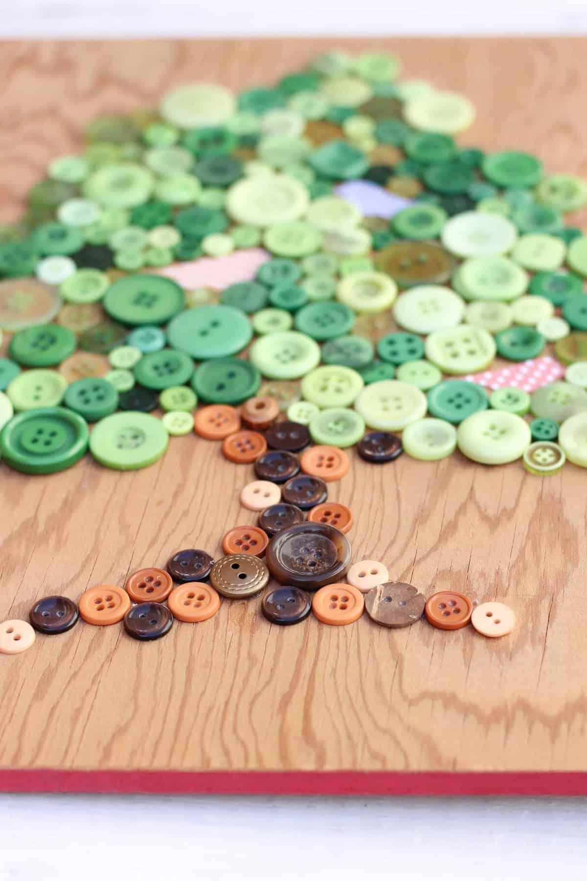 This DIY button art project makes a great Earth Day craft idea. It also looks sweet in a baby's room or nursery, especially as part of a gallery wall. Free printable template to make your own. Click for the full tutorial. | MakeAndDoCrew.com
