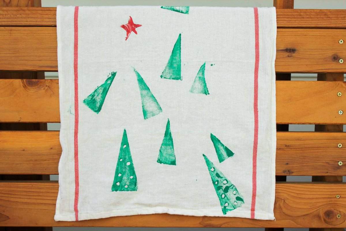 Potato stamp tea towel craft--a perfect DIY Christmas gift idea to make a bunch of at one time. They work out to about $1 each, which makes them an easy, inexpensive gift for everyone. This is a craft project parents can do with kids too! Click to view full step by step tutorial. | MakeAndDoCrew.com