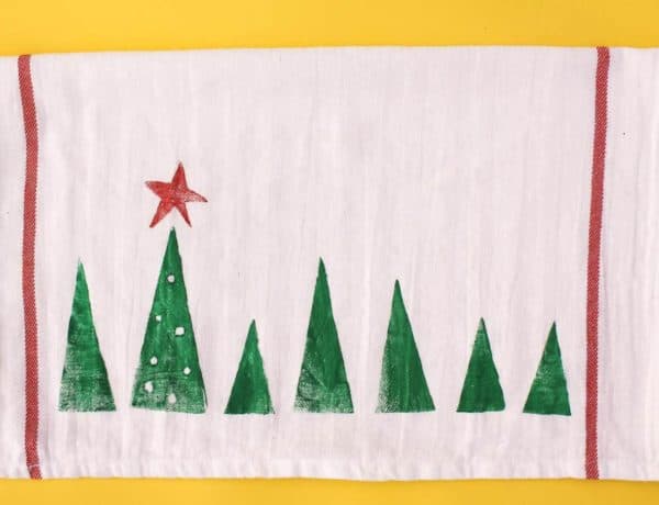 Potato stamp tea towel craft--a perfect DIY Christmas gift idea to make a bunch of at one time. They work out to about $1 each, which makes them an easy, inexpensive gift for everyone. This is a craft project parents can do with kids too! Click to view full step by step tutorial. | MakeAndDoCrew.com
