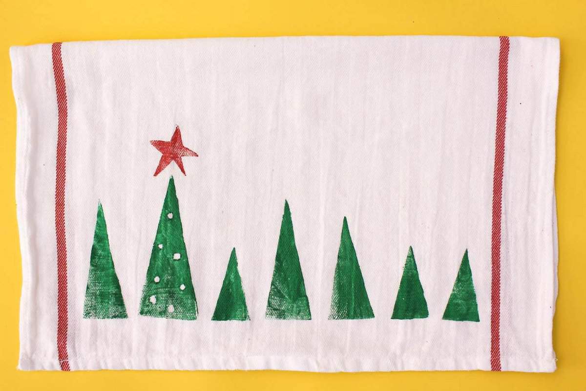 Potato stamp tea towel craft--a perfect DIY Christmas gift idea to make a bunch of at one time. They work out to about $1 each, which makes them an easy, inexpensive gift for everyone. This is a craft project parents can do with kids too! Click to view full step by step tutorial. | MakeAndDoCrew.com