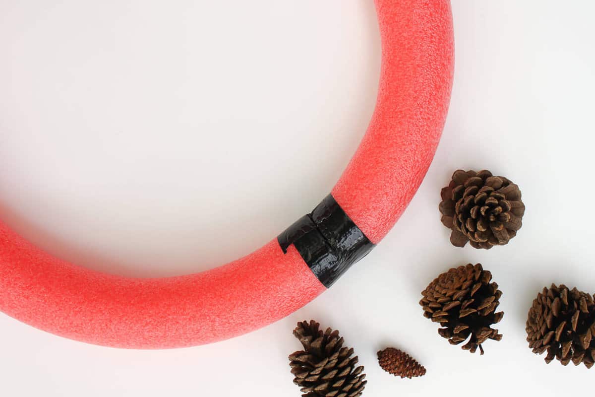 This DIY pinecone wreath is made with adorable little pom poms and costs less than $6 total! Perfect for the Christmas season and beyond. Click to view the full tutorial. | MakeAndDoCrew.com