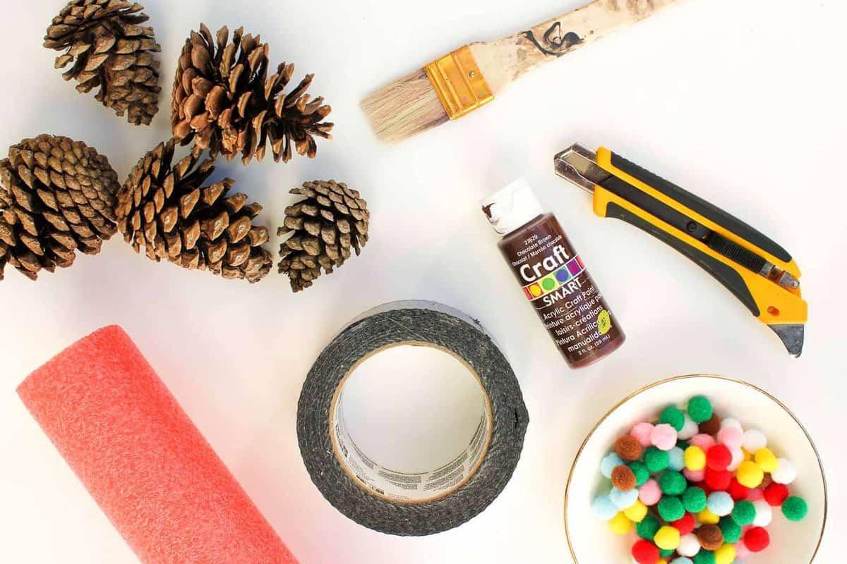 This DIY pinecone wreath is made with adorable little pom poms and costs less than $6 total! Perfect for the Christmas season and beyond. Click to view the full tutorial. | MakeAndDoCrew.com