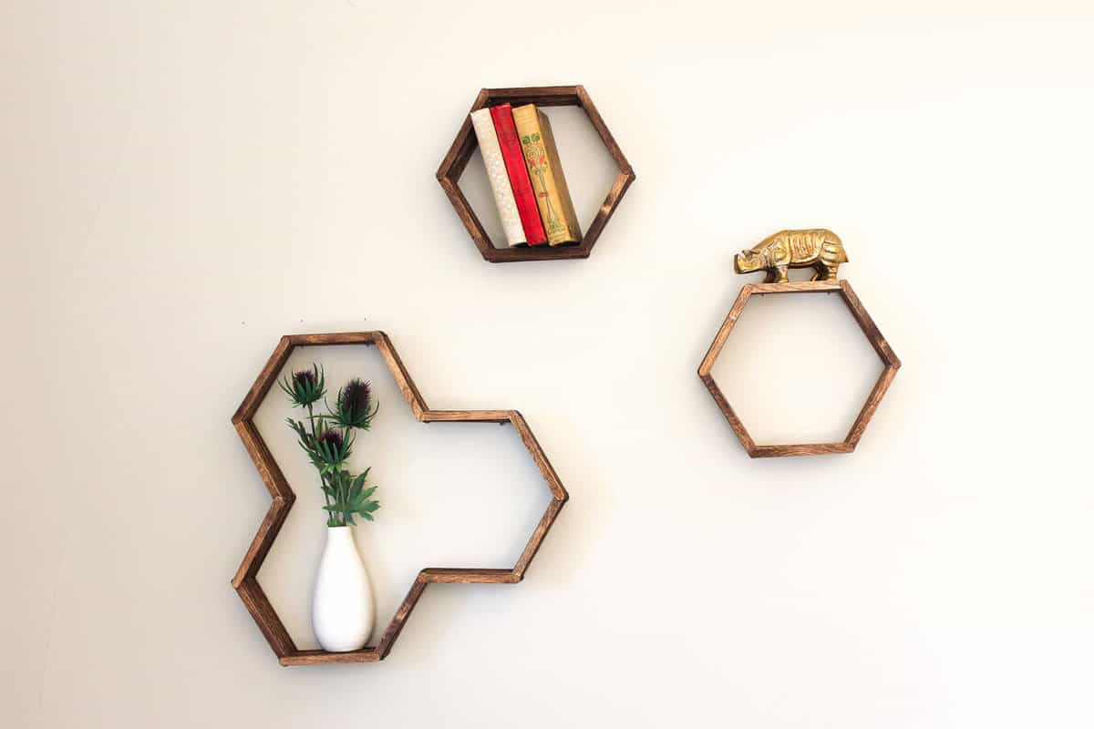 Make awesome mid century modern honeycomb shelves for less than $10 using popsicle sticks! These West Elm worthy hexagon shelves add warmth and dimension to any gallery wall and also look great on their own. Click for instructions and free downloadable template. | MakeAndDoCrew.com