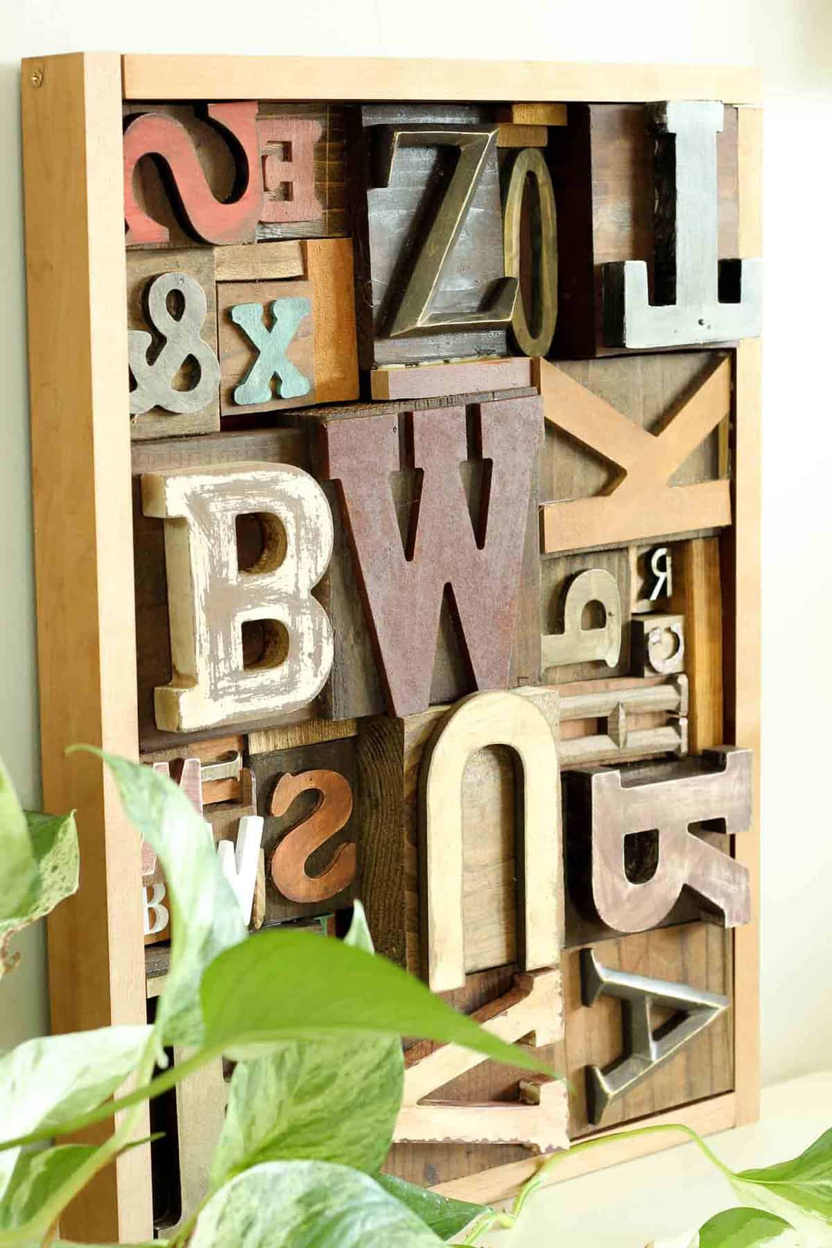 A DIY wall art idea that uses wooden letters (from any craft store) to make faux letterpress printing blocks. The vintage typography look adds so much charm to any room! Click for the full step-by-step tutorial. | MakeAndDoCrew.com