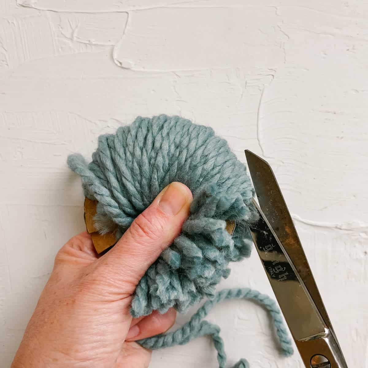 How to cut the wrapped strands of yarn to make a fluffy pom pom.