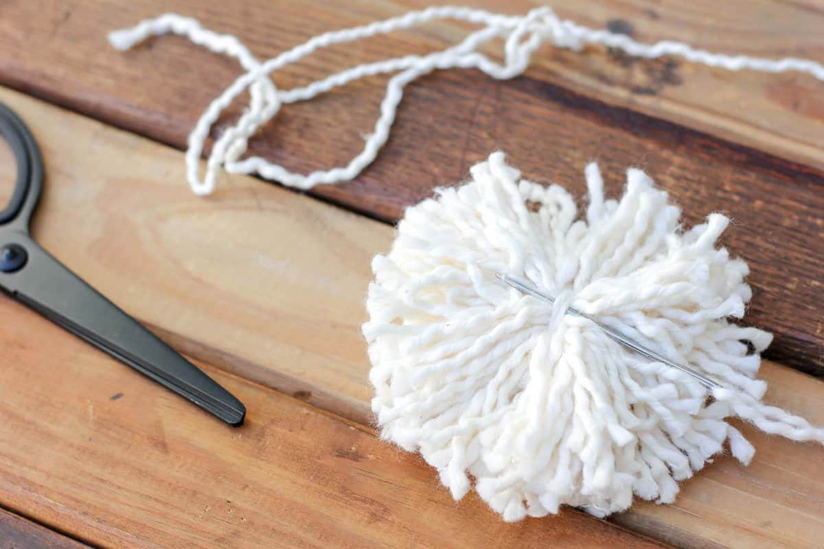A yarn pom pom with a tapestry needle.