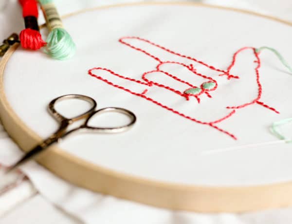 This free embroidery pattern is based on the American Sign Language sign for "I love you." Perfect DIY art for a baby nursery, playroom or Valentine's Day gift idea. Download the design at MakeAndDoCrew.com.