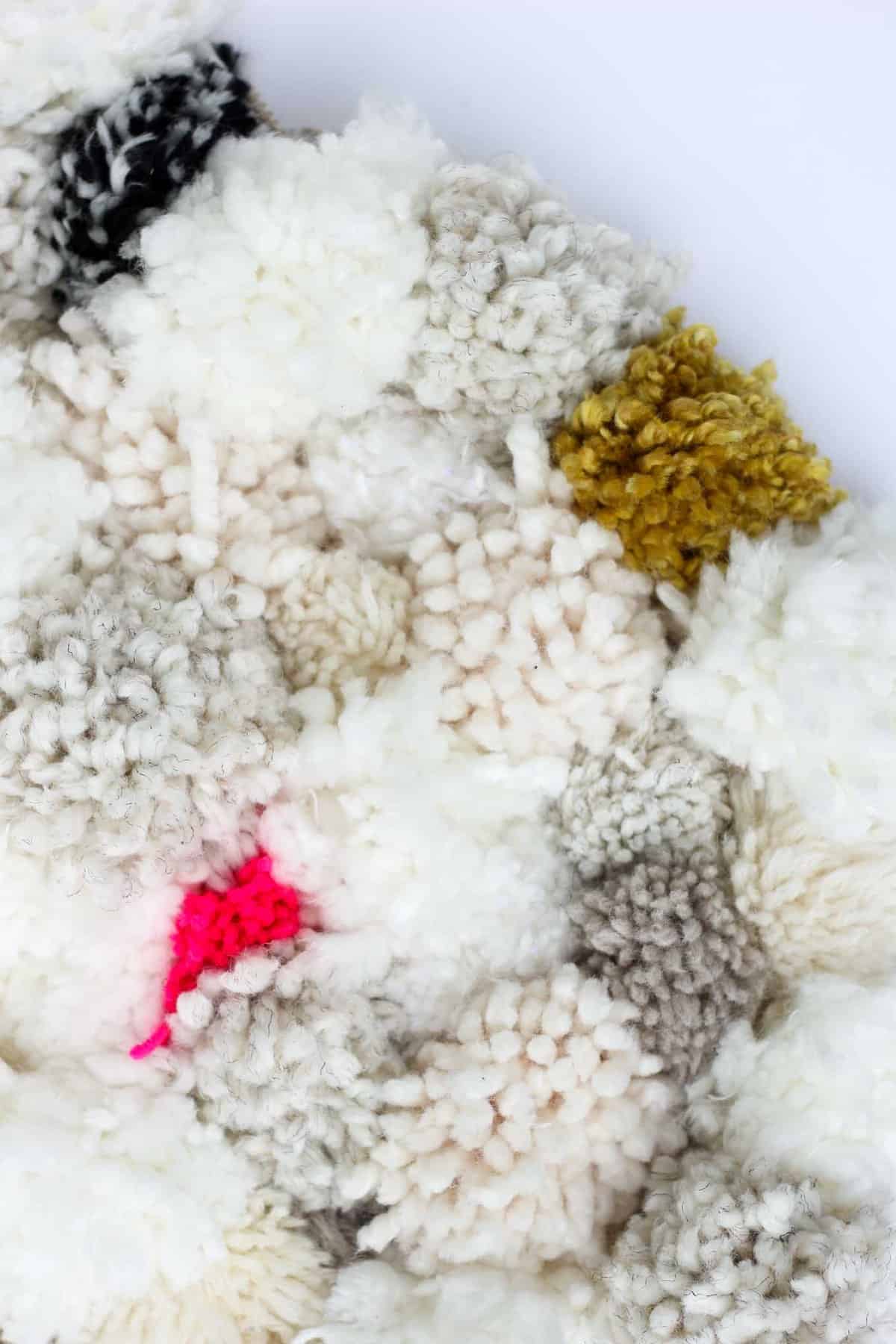 How to make a pom pom rug! This soft, scrumptiously squishy DIY pom pom rug takes very few skills to create and is a great way to use up a bunch of scrap yarn! Click for full tutorial. | MakeAndDoCrew.com