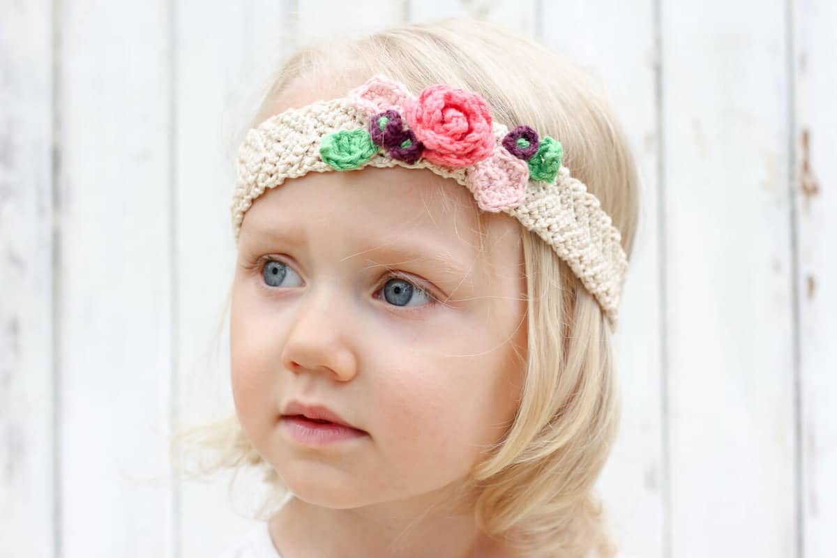 This free crochet flower headband pattern is surprisingly easy and it makes an adorable headpiece for a young flower girl in a wedding (or a bohemian beauty of any age)! Sizes include newborn, baby, toddler, child, teen and adult. | MakeAndDoCrew.com