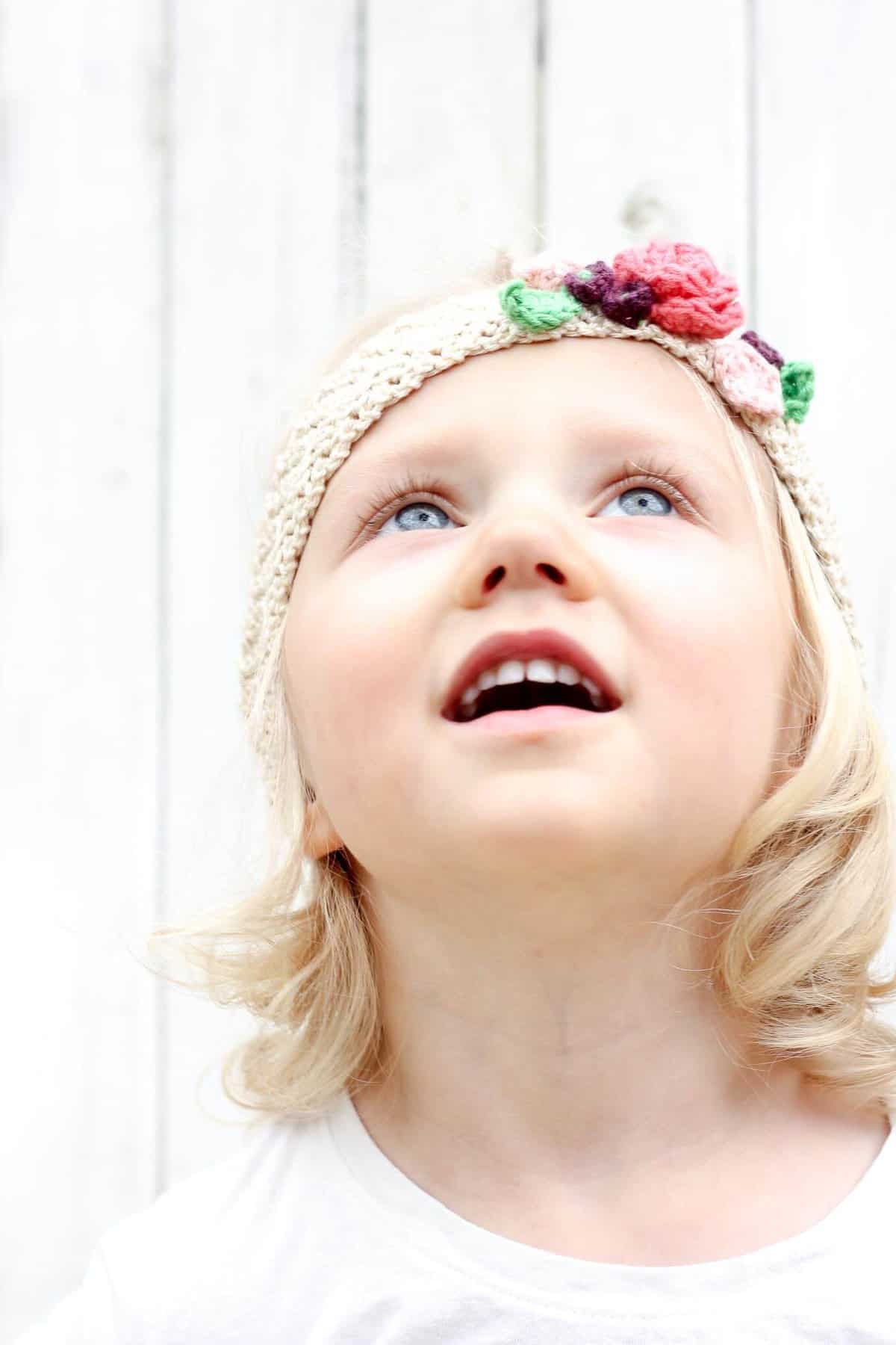 This free crochet headband pattern with flowers is surprisingly easy and it makes an adorable headpiece for a young flower girl in a wedding (or a bohemian beauty of any age)! Sizes include newborn, baby, toddler, child, teen and adult. | MakeAndDoCrew.com