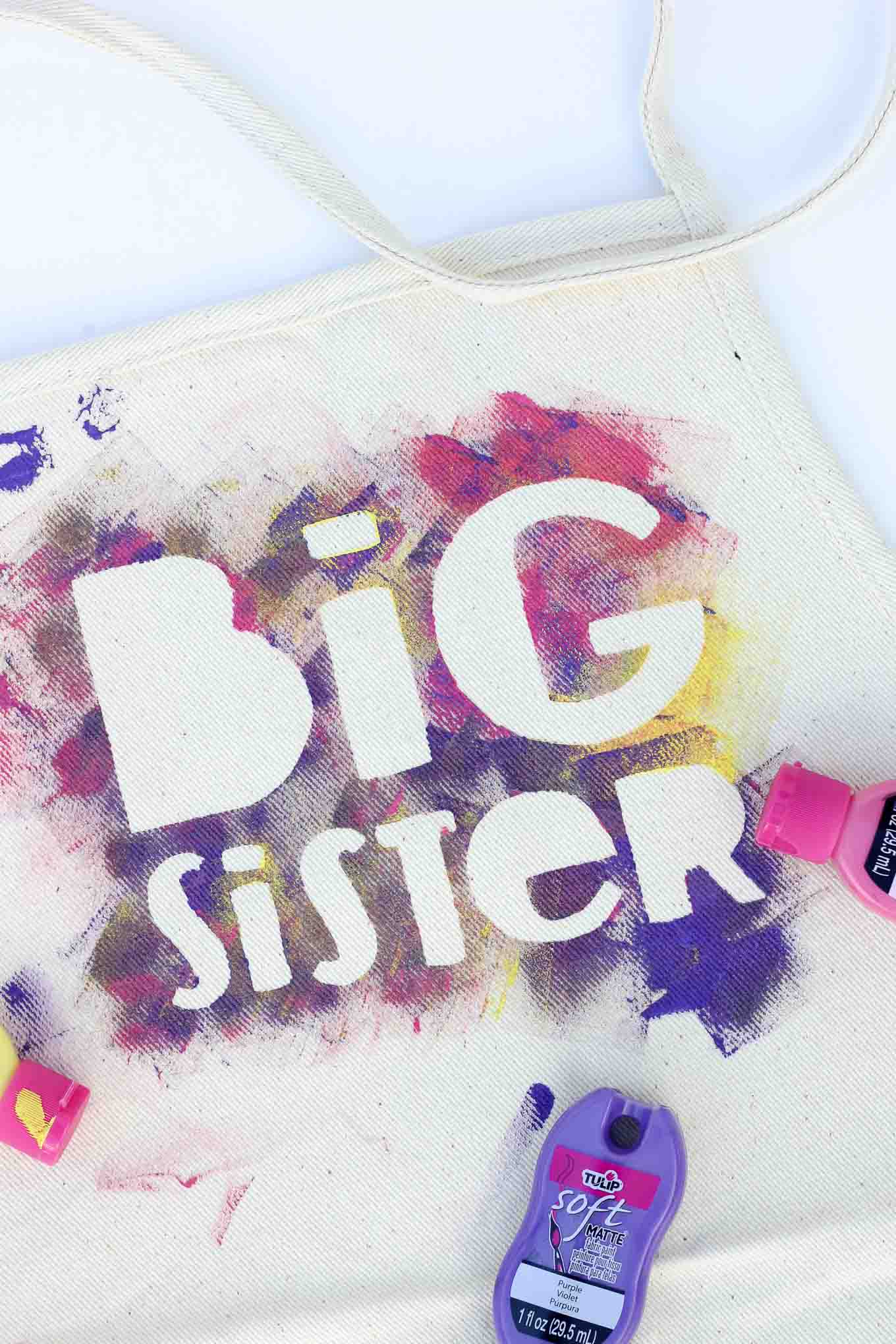 This easy kids craft is an awesome way to prepare older siblings for their new role as the “helper” in the family before a new baby arrives. The DIY apron also makes a great big brother / big sister gift idea kids can make themselves. Free template! | MakeAndDoCrew.com