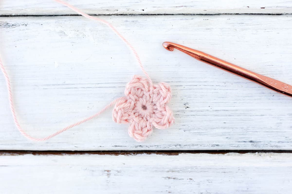 Cherry blossom crochet flower with a crochet hook.