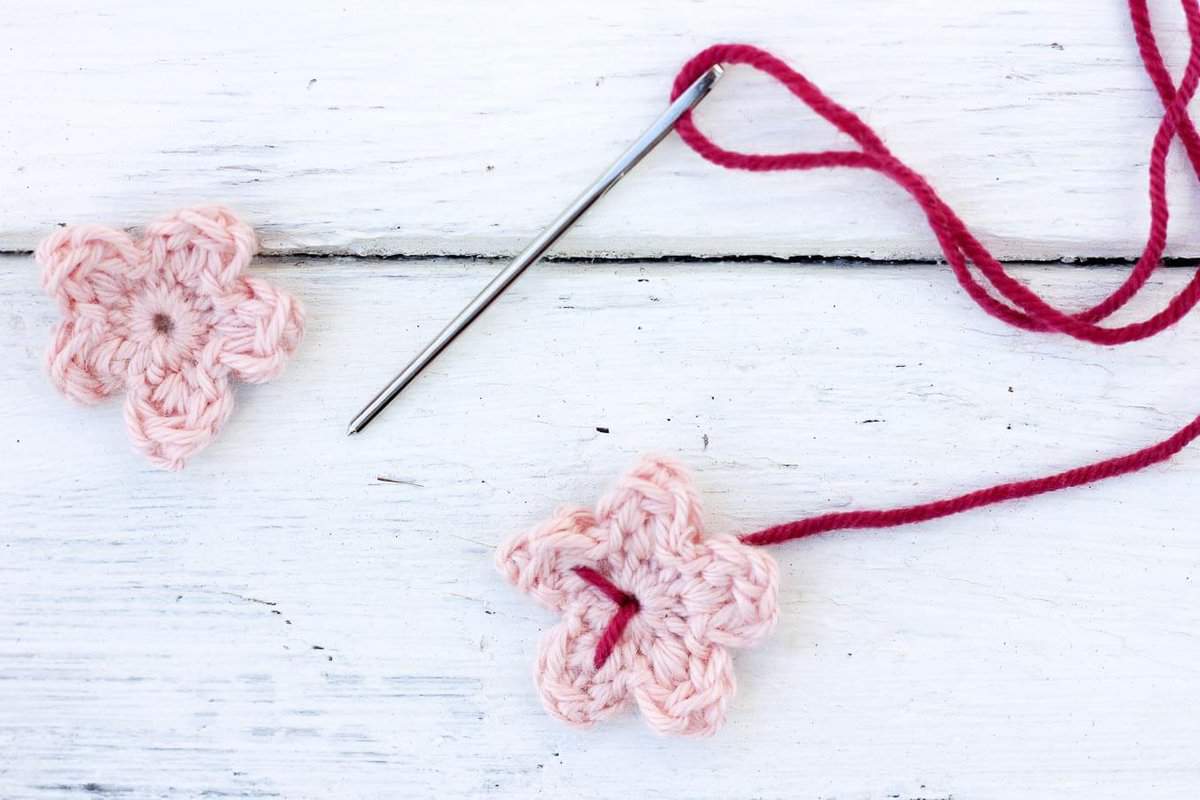 An in-progress crochet cherry blossom with a tapestry needle.