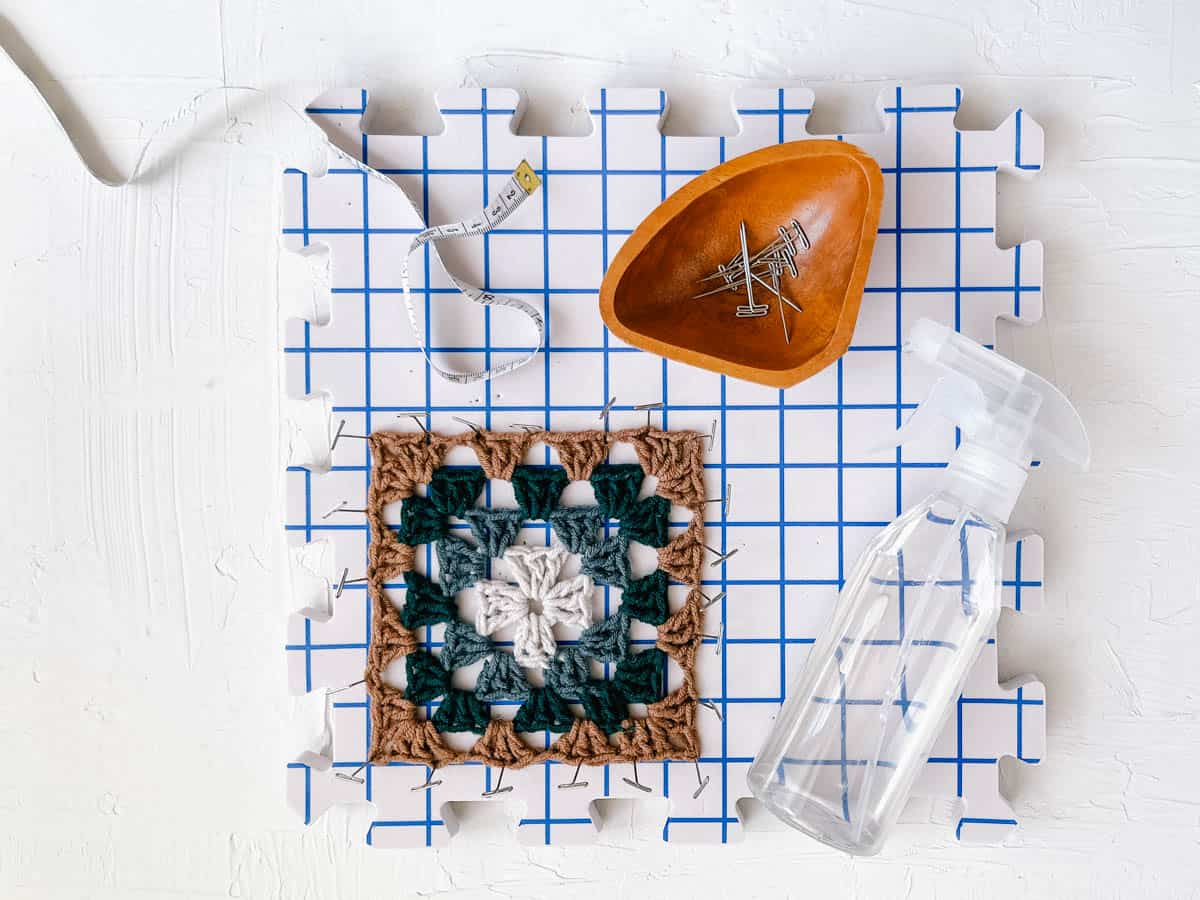 Crochet granny square drying on a blocking board.