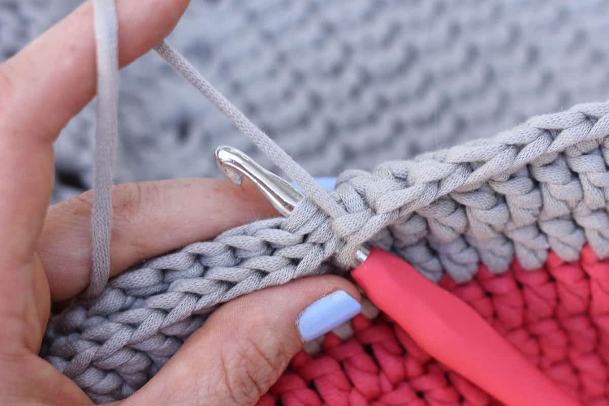 close up of crochet hook joining two pillow squares together