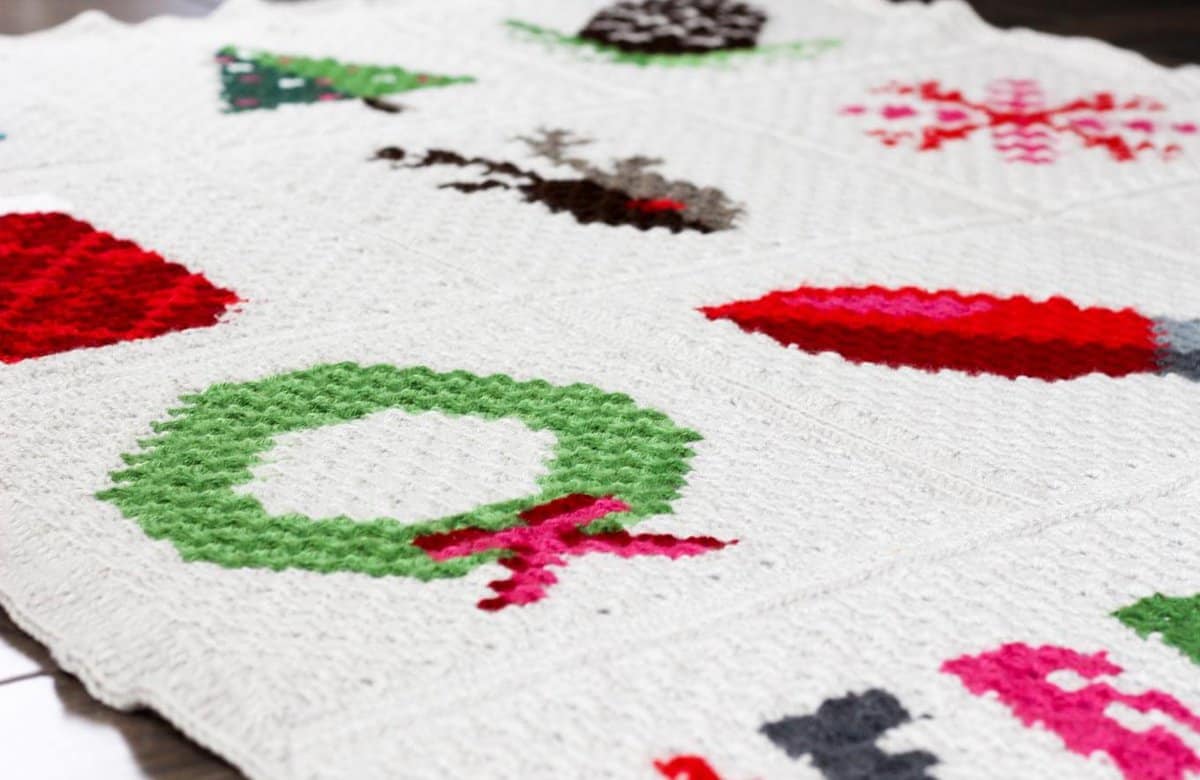 Make an heirloom your family can snuggle up with year after year with this free corner to corner crochet Christmas afghan pattern! These modern c2c Christmas graphs make perfect winter pillows too. Crocheted with Lion Brand Vanna's Choice yarn.