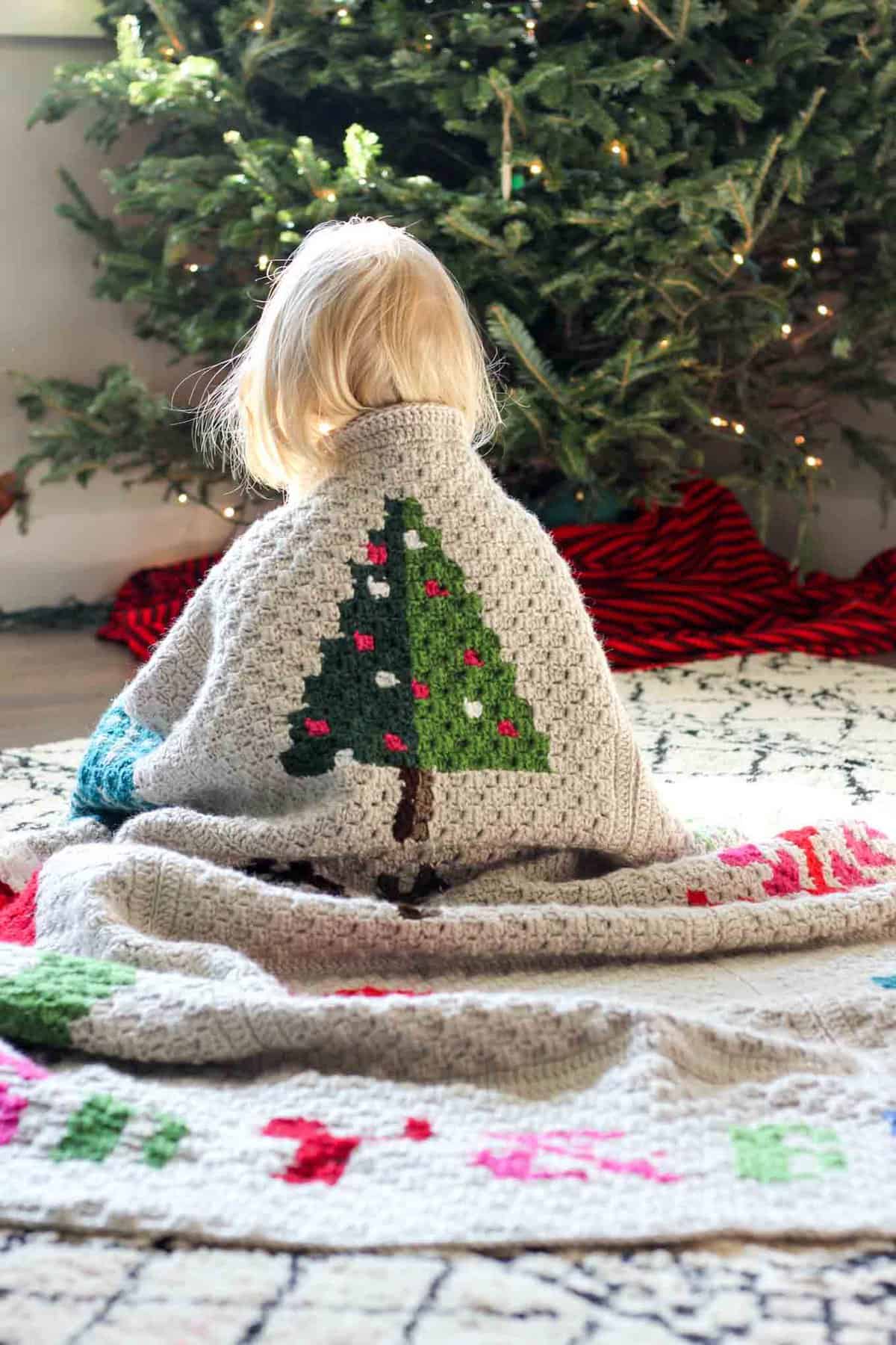 Make an heirloom your family can snuggle up with year after year with this free corner to corner crochet Christmas afghan pattern! These modern c2c Christmas graphs make perfect winter pillows too. Crocheted with Lion Brand Vanna's Choice yarn.