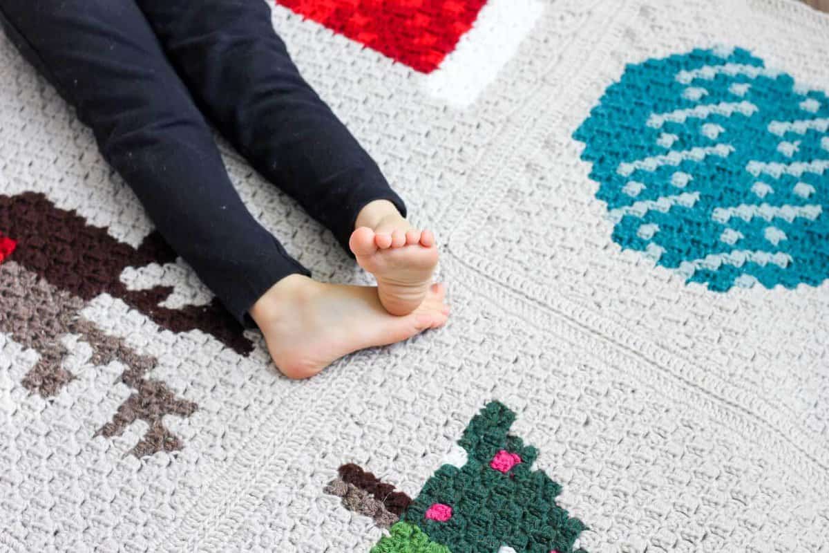 Make an heirloom your family can snuggle up with year after year with this free corner to corner crochet Christmas afghan pattern! These modern c2c Christmas graphs make perfect winter pillows too. Crocheted with Lion Brand Vanna's Choice yarn.