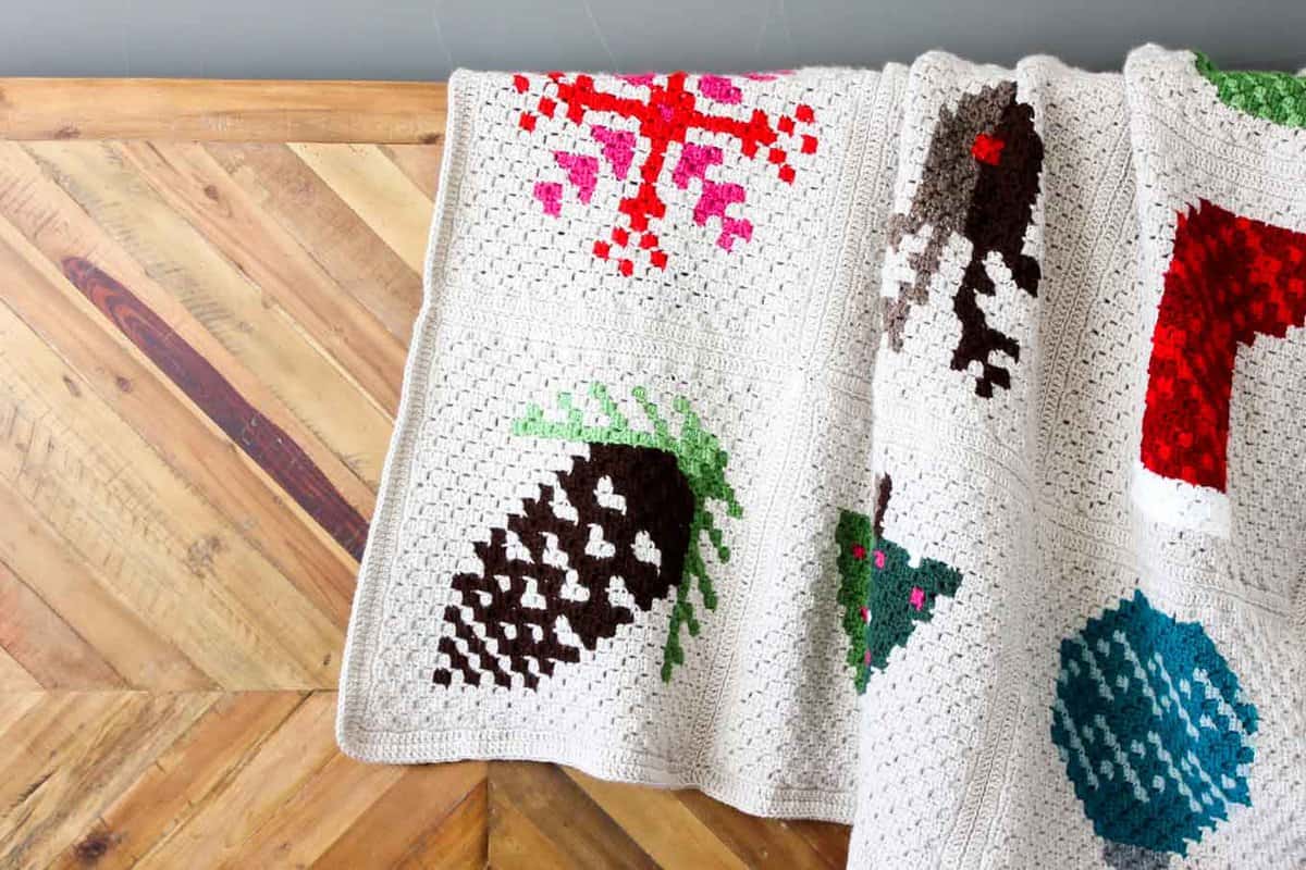 Make an heirloom your family can snuggle up with year after year with this free corner to corner crochet Christmas afghan pattern! These modern c2c Christmas graphs make perfect winter pillows too. Crocheted with Lion Brand Vanna's Choice yarn.