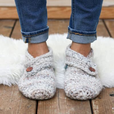 This free crochet slippers pattern will satisfy the modern minimalist in you while also making you feel like a gift giving hero. They make the perfect gift for teachers, new moms, a friend who is sick and anyone else you want to wrap up in a little bit of love. Free women's slipper pattern from MakeAndDoCrew.com using Lion Brand Wool Ease Thick and Quick in "Fossil" and "Blueberry."
