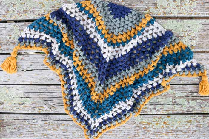 This crochet triangle scarf looks like the granny or bobble stitch, but it's actually the bead stitch. The tassels complete this modern scarf. Free pattern and video tutorial!