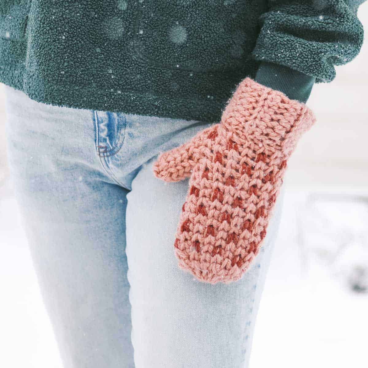 One crochet mitten with small pink hearts.