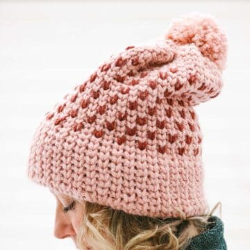 Side view of a woman wearing a pink crochet hat that looks knit.