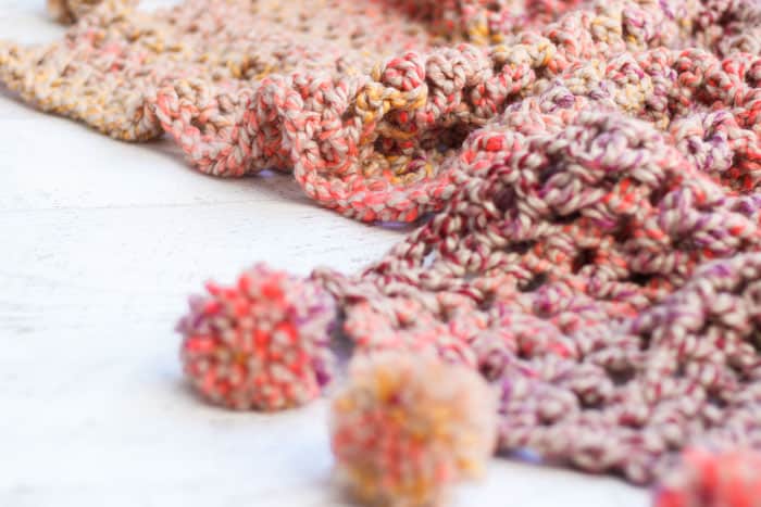 Free fast crochet afghan pattern that features pom pom tassels along the edges. Great beginner crochet blanket tutorial. Crochet blanket pattern that can be made in less than 5 hours!
