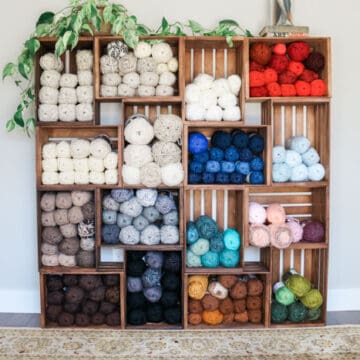 DIY wooden crate shelves holding a variety of skeins of colorful yarn.
