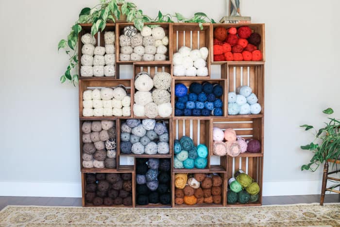 DIY wooden crate shelves holding a variety of skeins of colorful yarn.