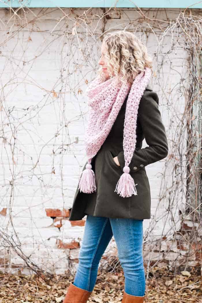 Woman wearing modern crochet triangle scarf with tassels. Free crochet pattern featuring Lion Brand Touch of Alpaca yarn.