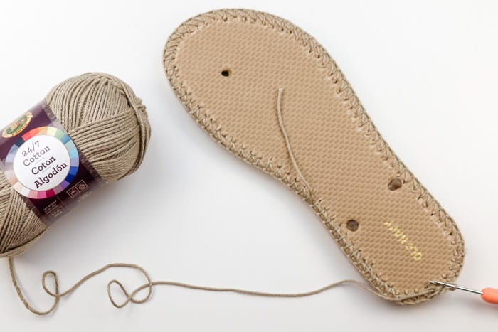 The first step of creating crochet shoes with flip flop soles using Lion Brand 24/7 Cotton yarn in the color "Taupe."