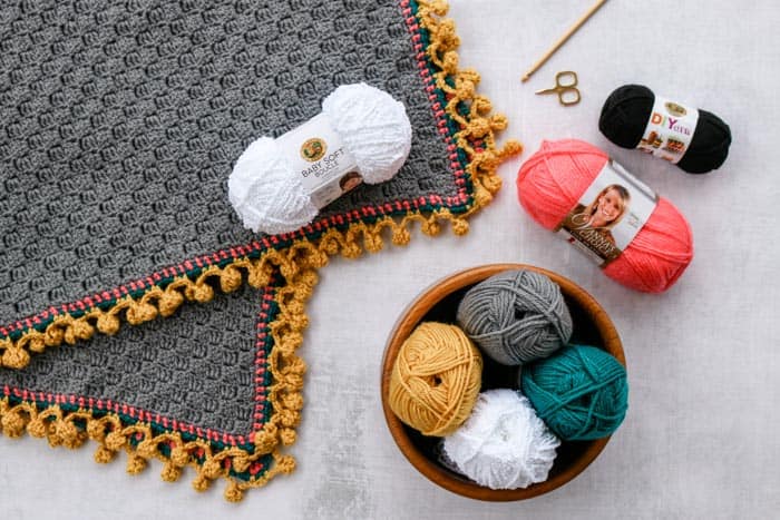 Crochet blanket with pom pom edging border. Free pattern and video tutorial on how to make this llama c2c blanket featuring Lion Brand Vanna's Choice and Baby Soft Boucle.