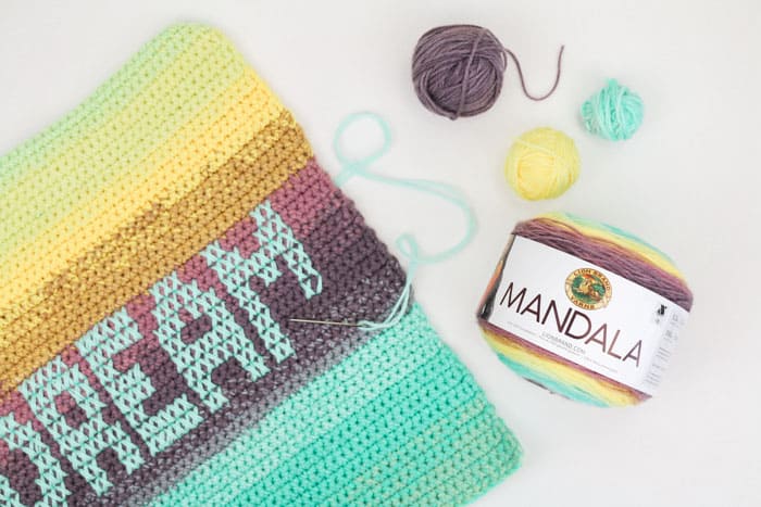 Paint your perfect palette with this ombre pillows made from gorgeous Lion Brand Mandala yarn cakes. Three strands held together throughout creates a chunkier look while the cross stitch detailing allows you to personalize a message for everyone you know. 