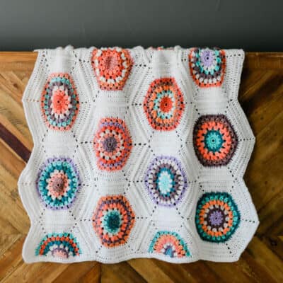 Vintage-looking, gender neutral crochet blanket pattern made from crochet hexagons that are joined as you go. Free pattern + video tutorial featuring Lion Brand Mandala, Cupcake and Pound of Love yarns.