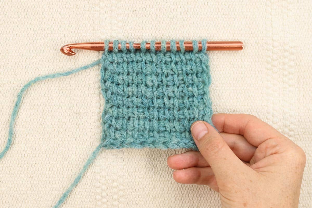 A blue swatch of Tunisian crochet simple stitch on a standard crochet hook.
