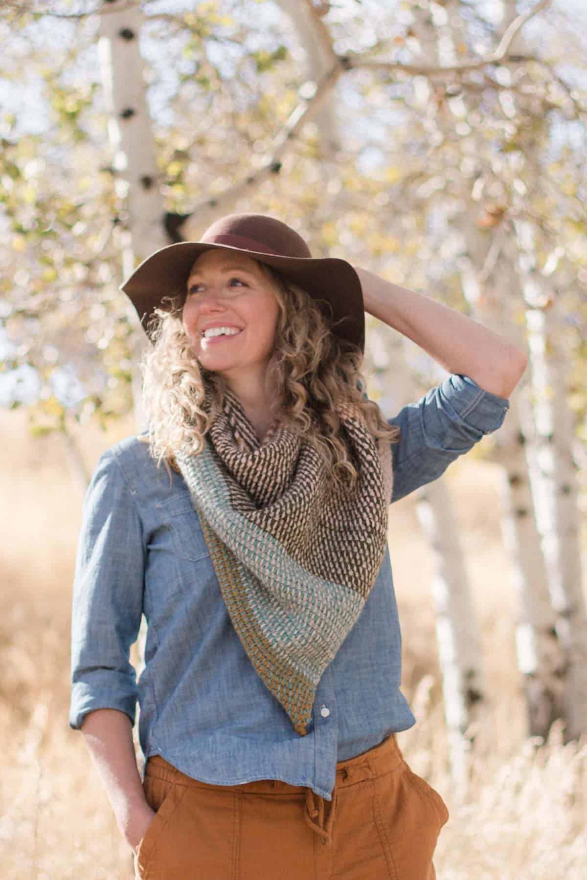 Woman wearing a Tunisian crochet shawl that's made with TSS in beautiful striped colors.