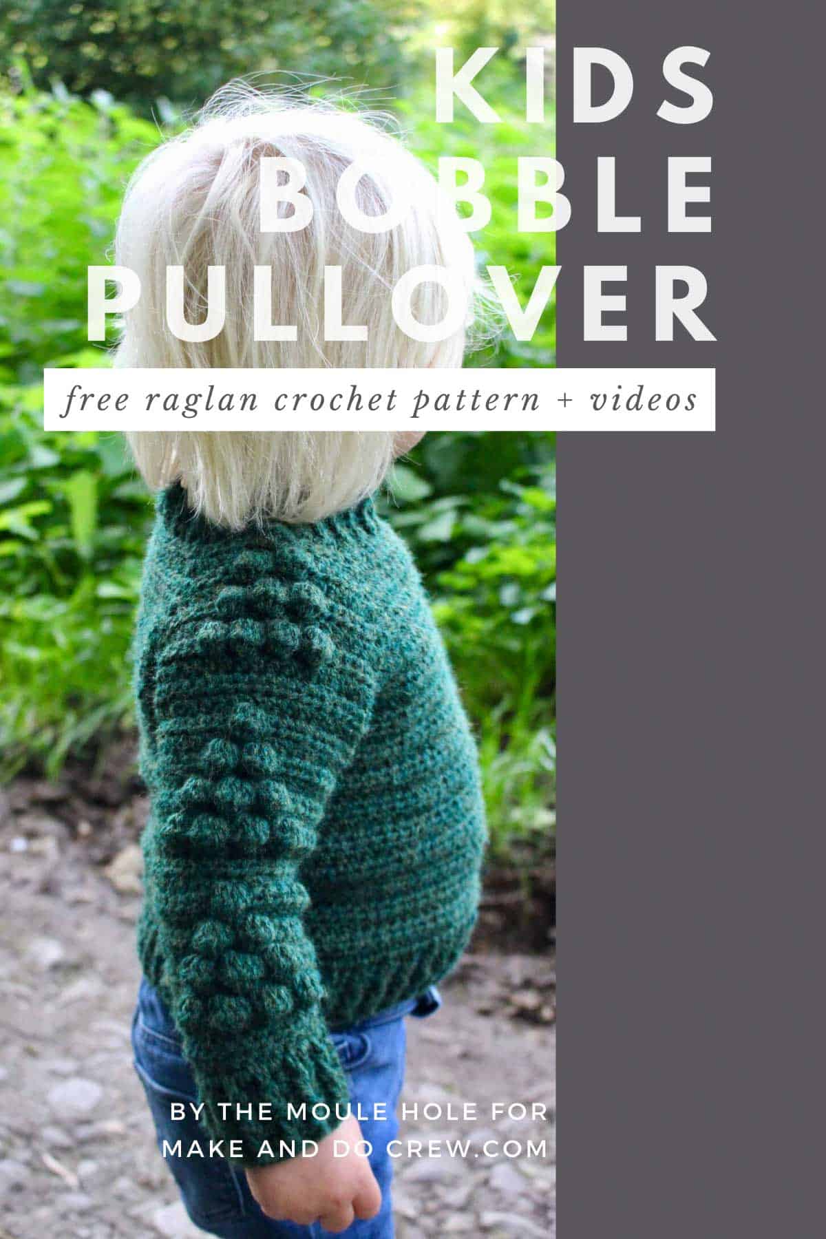 Toddler boy standing looking at green meadow. He is wearing a pullover crochet sweater with a tree bobble motif on the sleeves. Free pattern and tutorial.
