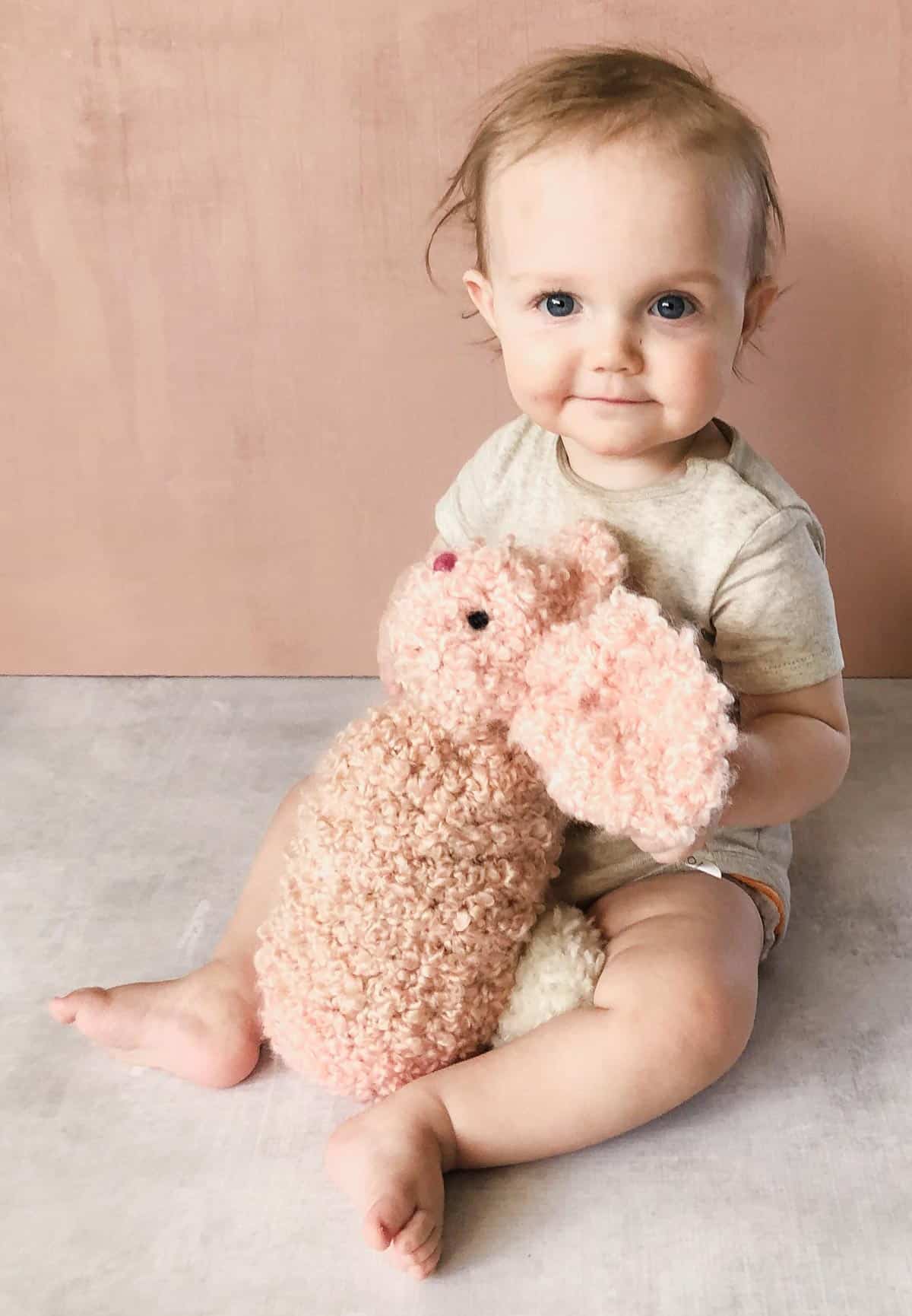 Cute baby snuggling a giant crochet bunny toy made from a square or rectangle.