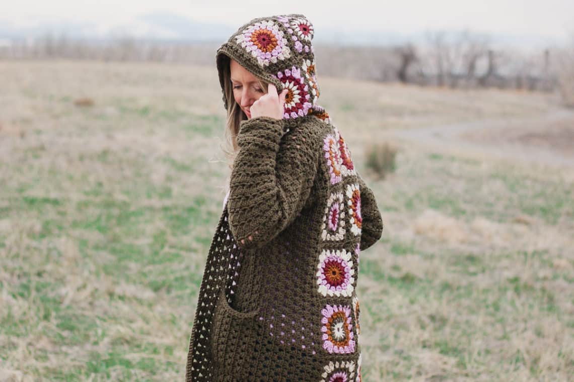 Woman standing in a field of granny wearing a vintage style crochet granny square sweater similar to the cardigan Rebecca Pearson wore on This Is Us.