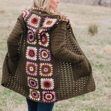 Woman standing in a field of granny wearing a vintage style crochet granny square sweater similar to the cardigan Rebecca Pearson wore on This Is Us.
