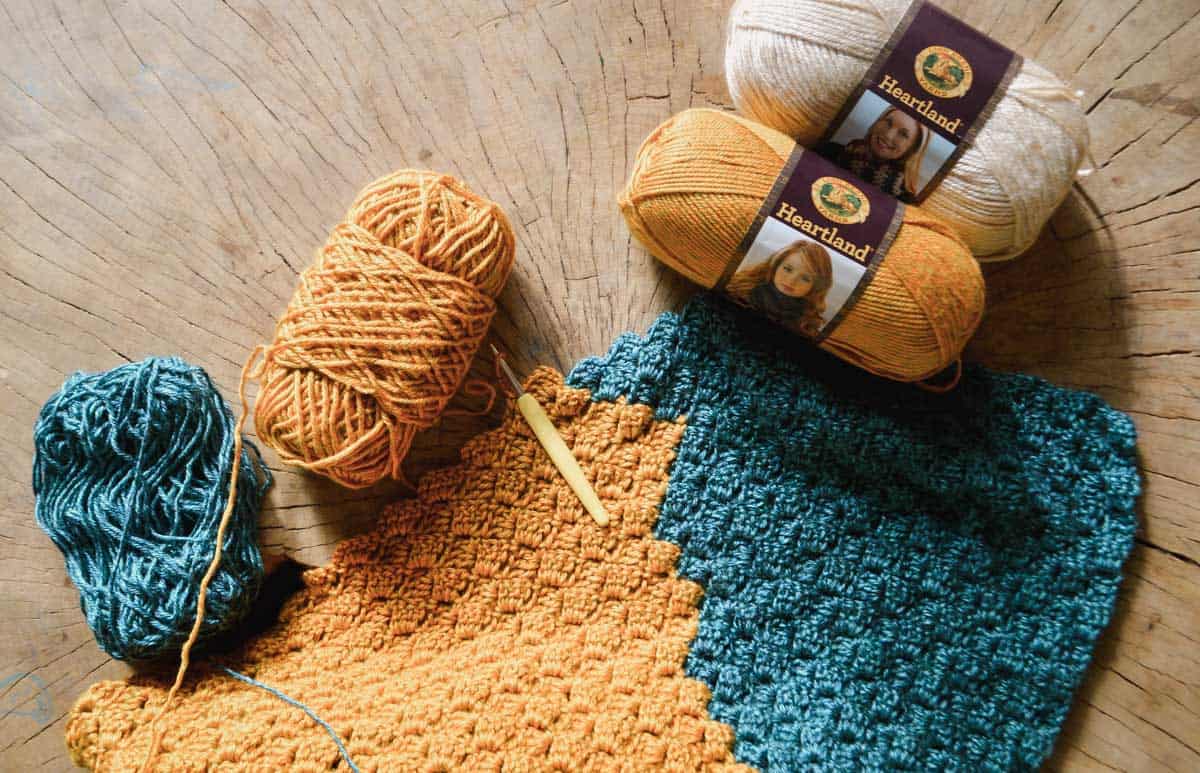 Two skeins of Lion Brand Heartland yarn attached to a work in progress corner to corner crochet afghan.