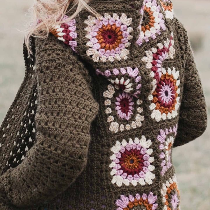 The back of a vintage-looking crochet granny stitch cardigan sweater with a hood.