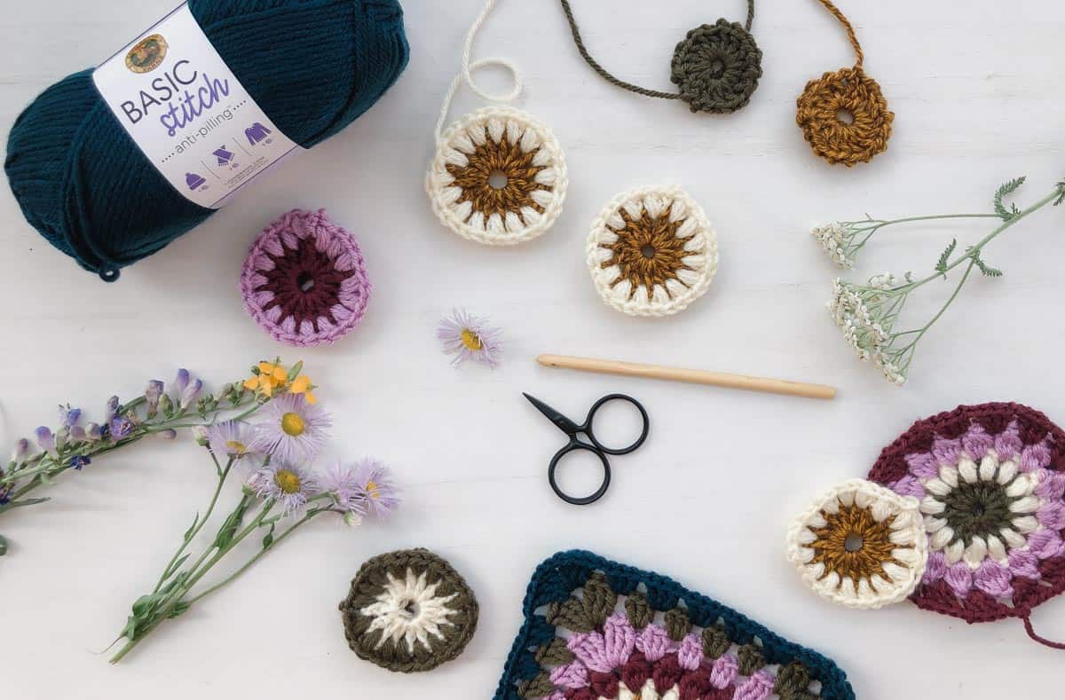 A scattering of in progress modern crochet granny squares made with Lion Brand Basic Stitch yarn.