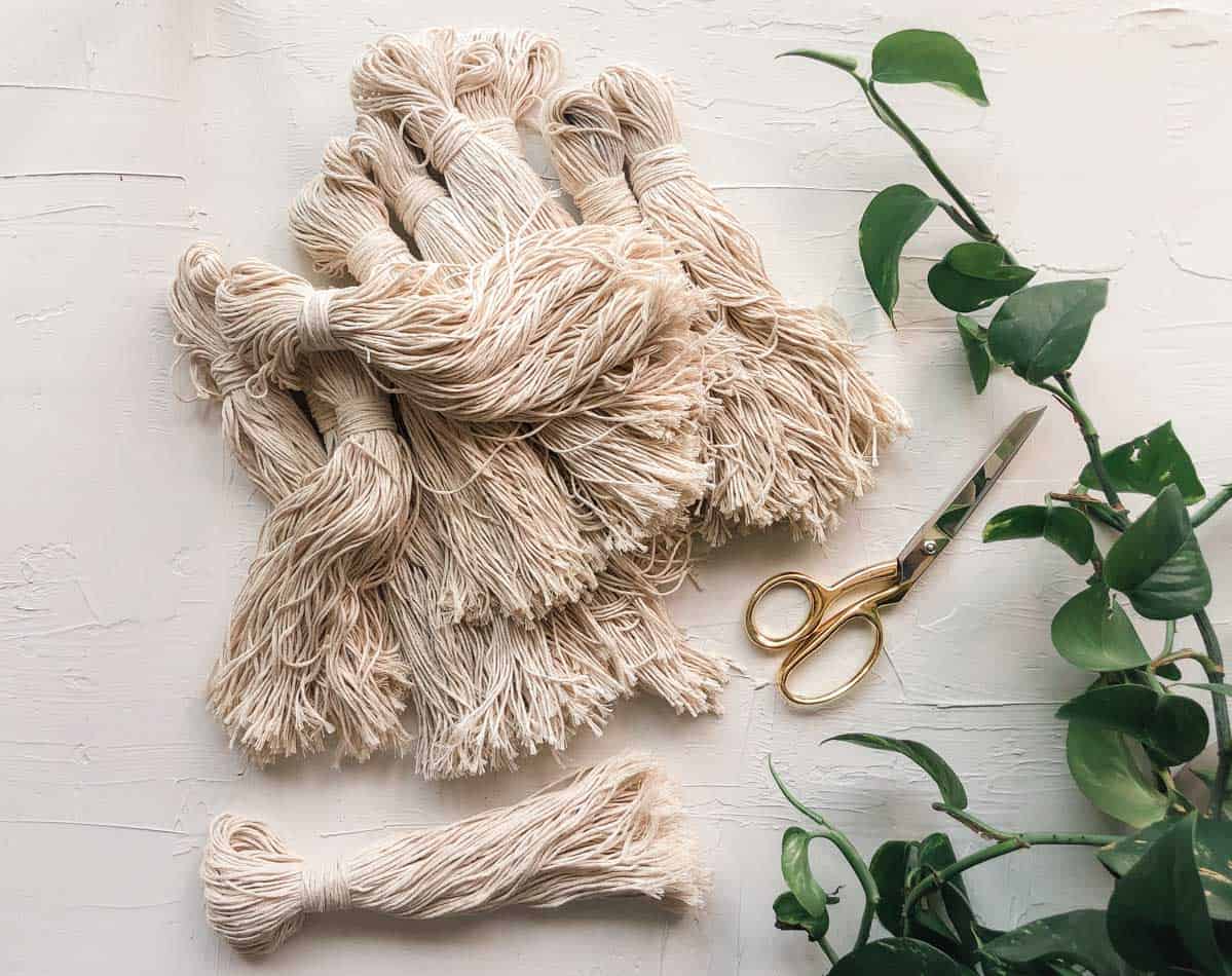 A pile of tassels made from cotton twine that are being used for a DIY tassel wall hanging. 