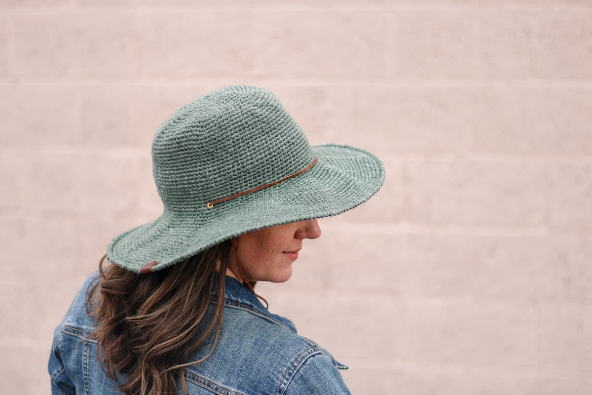 Brown haired woman wearing a crocheted sun hat with a stiff brim.