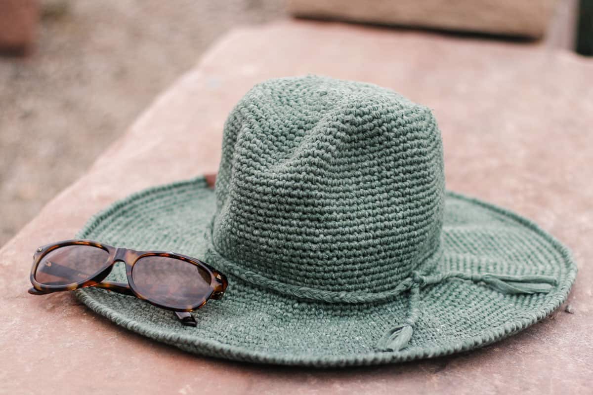 A crochet fedora sun hat sitting on a rock.