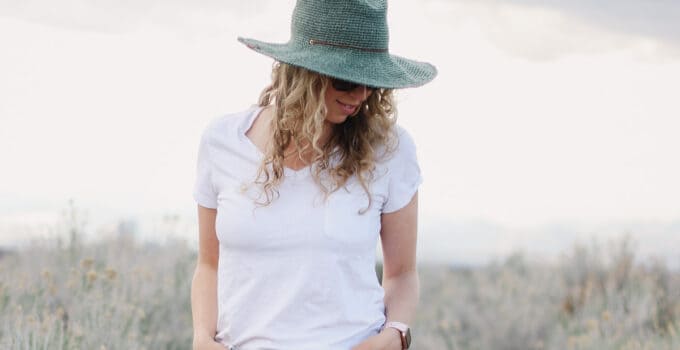 Woman wearing a raffia crochet sun hat in the fedora style.