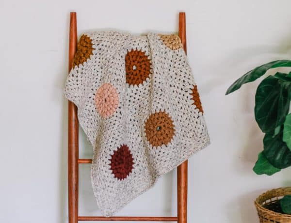 Crochet puff stitch granny square blanket hanging on a mid century blanket ladder.