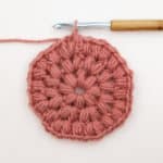 A crochet puff stitch circle coaster in progress.